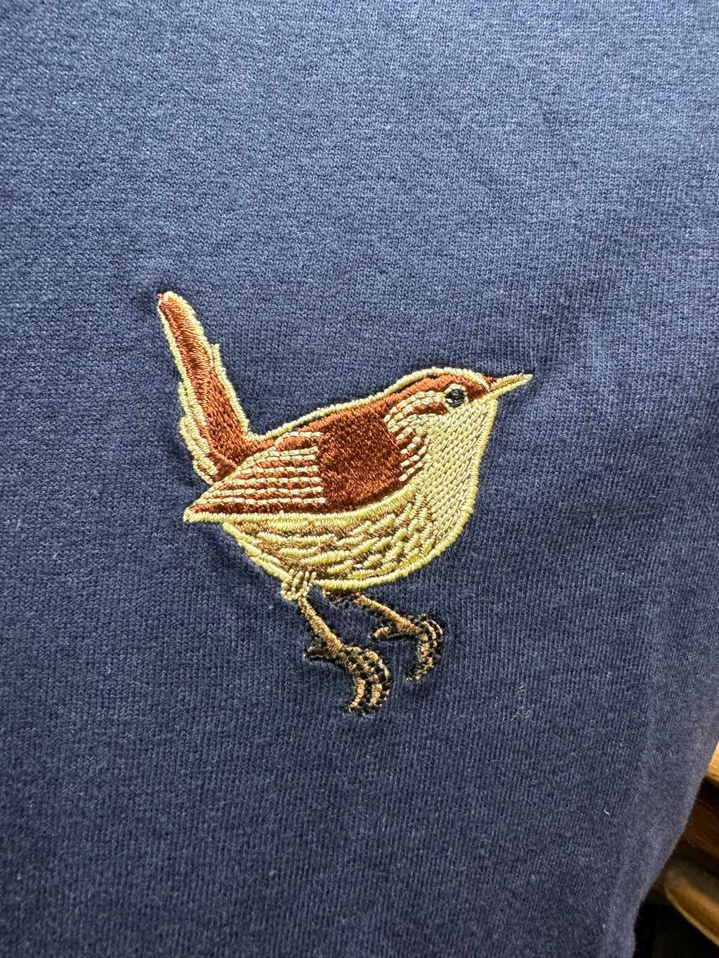 Embroidered bird design on a blue fabric background
