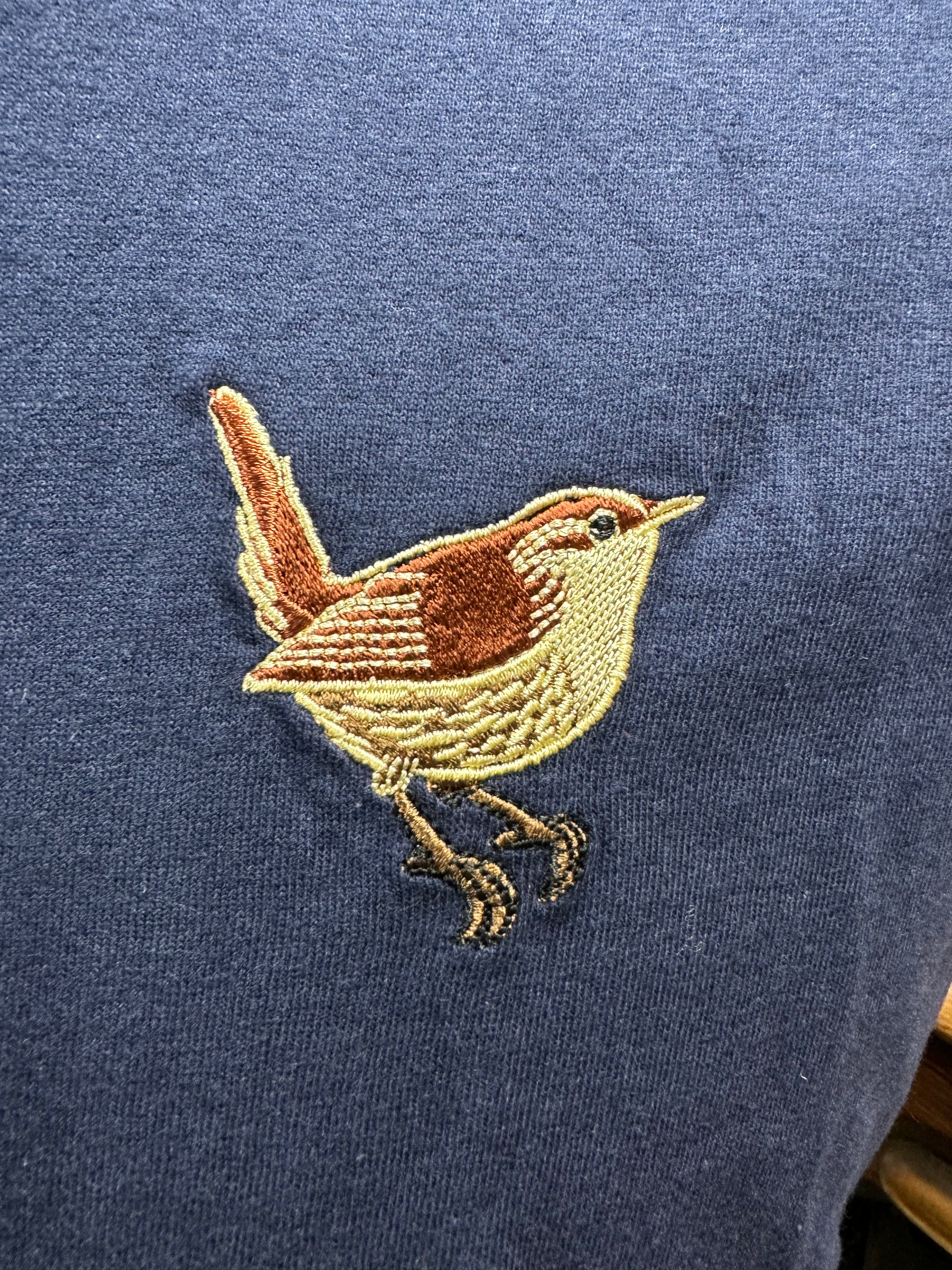 Embroidered bird design on a blue fabric background