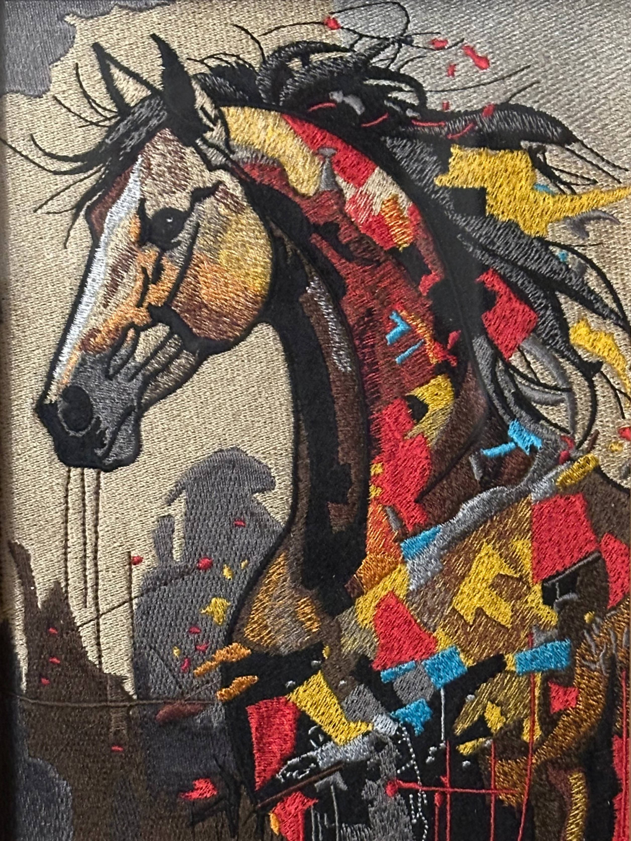Colorful embroidered artwork of a horse head with a wooden frame