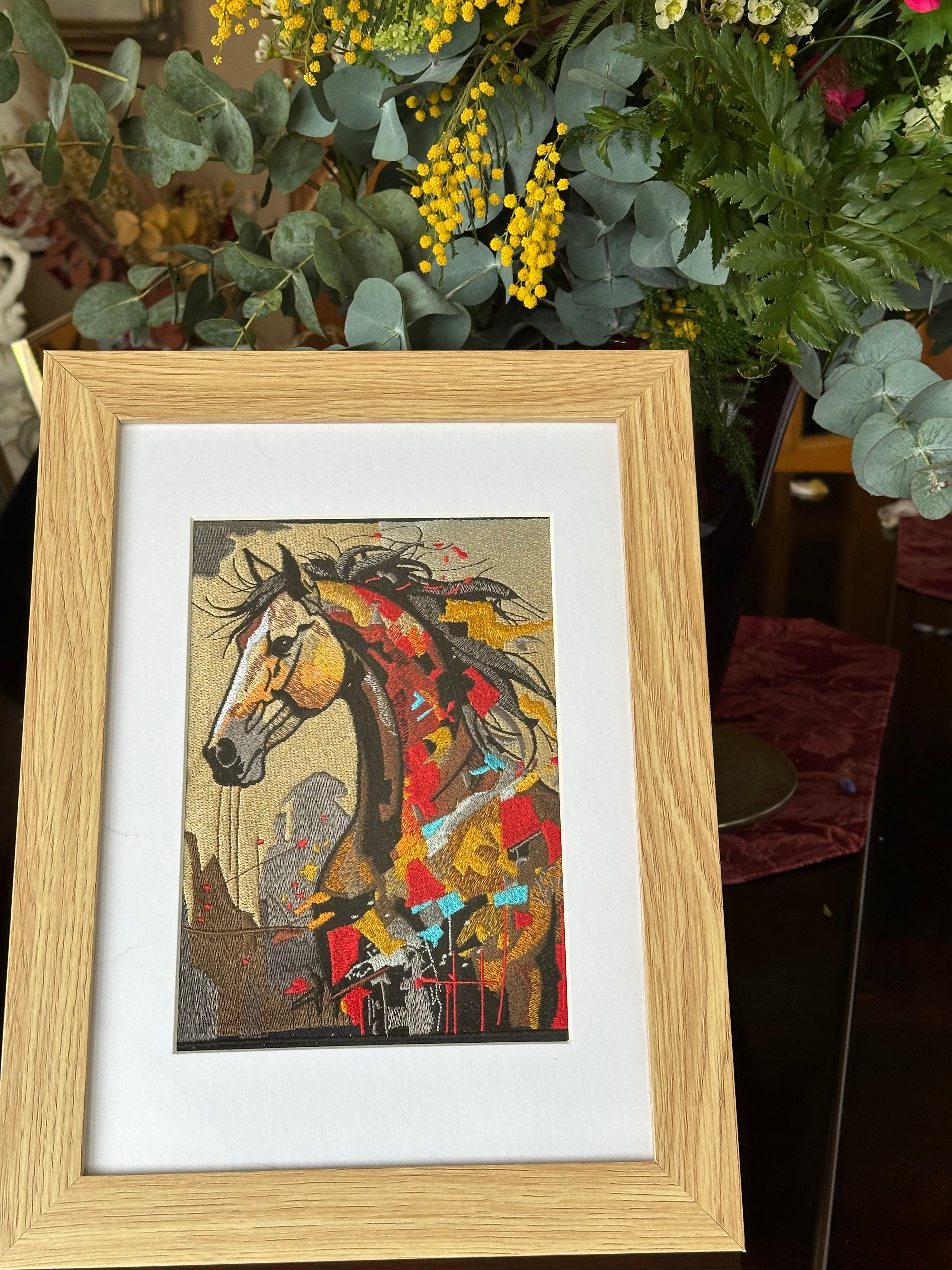 Framed artwork of a colorful horse portrait with a wooden frame, surrounded by greenery.