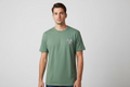 Man wearing a green t-shirt with a logo on a gray background
