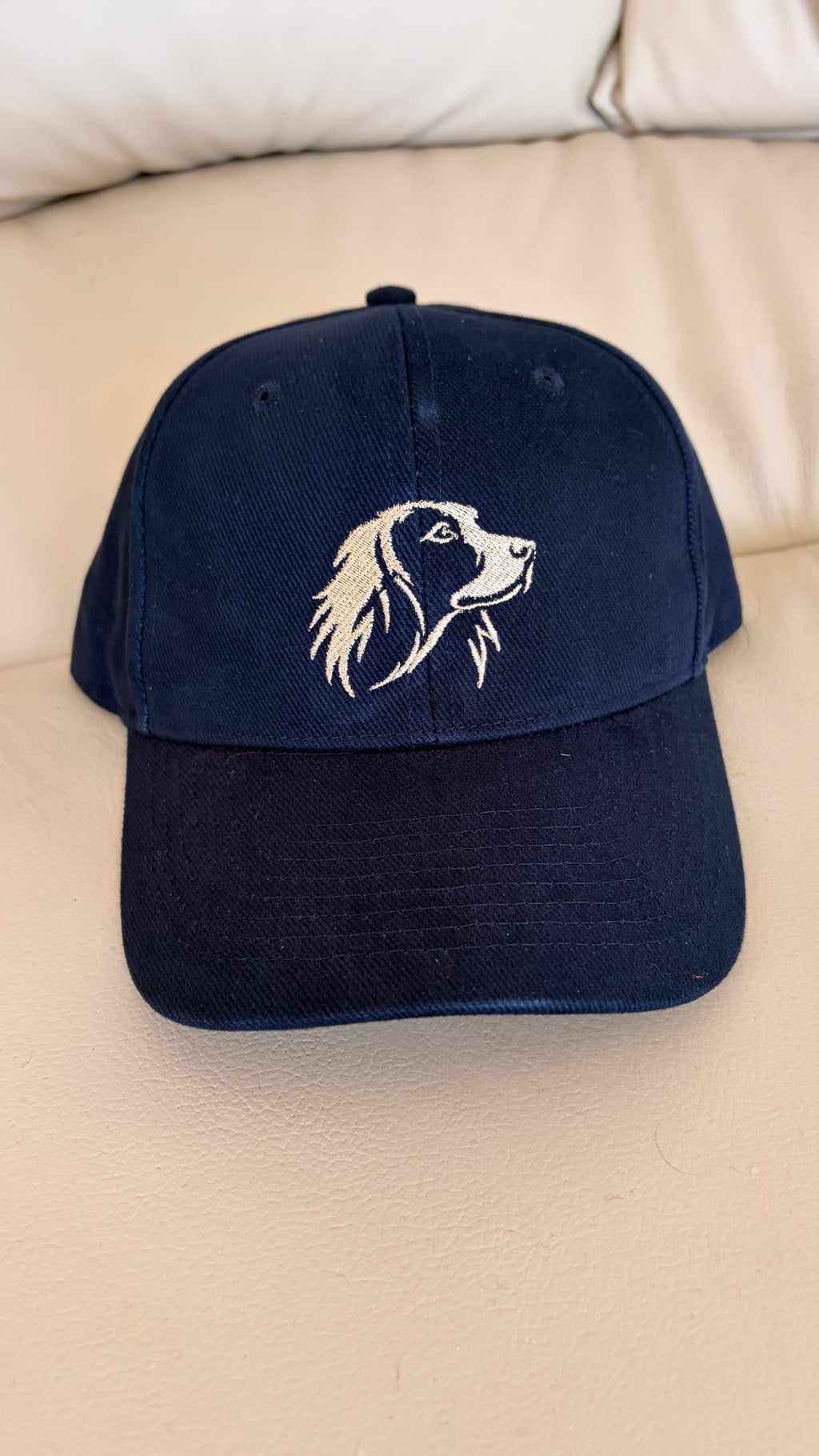 Navy blue cap with a dog illustration on a beige surface
