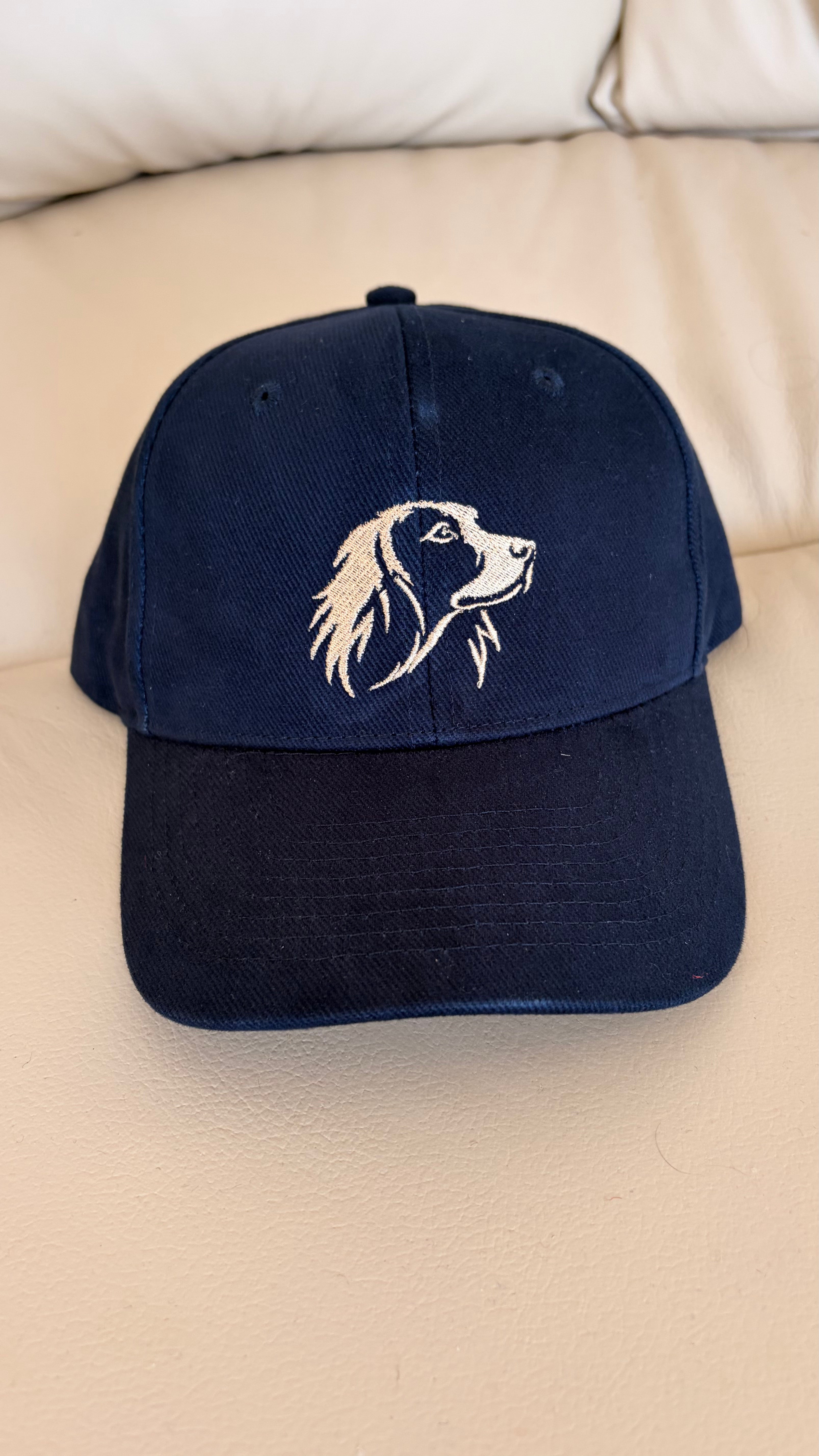 Navy blue cap with a dog illustration on a beige surface
