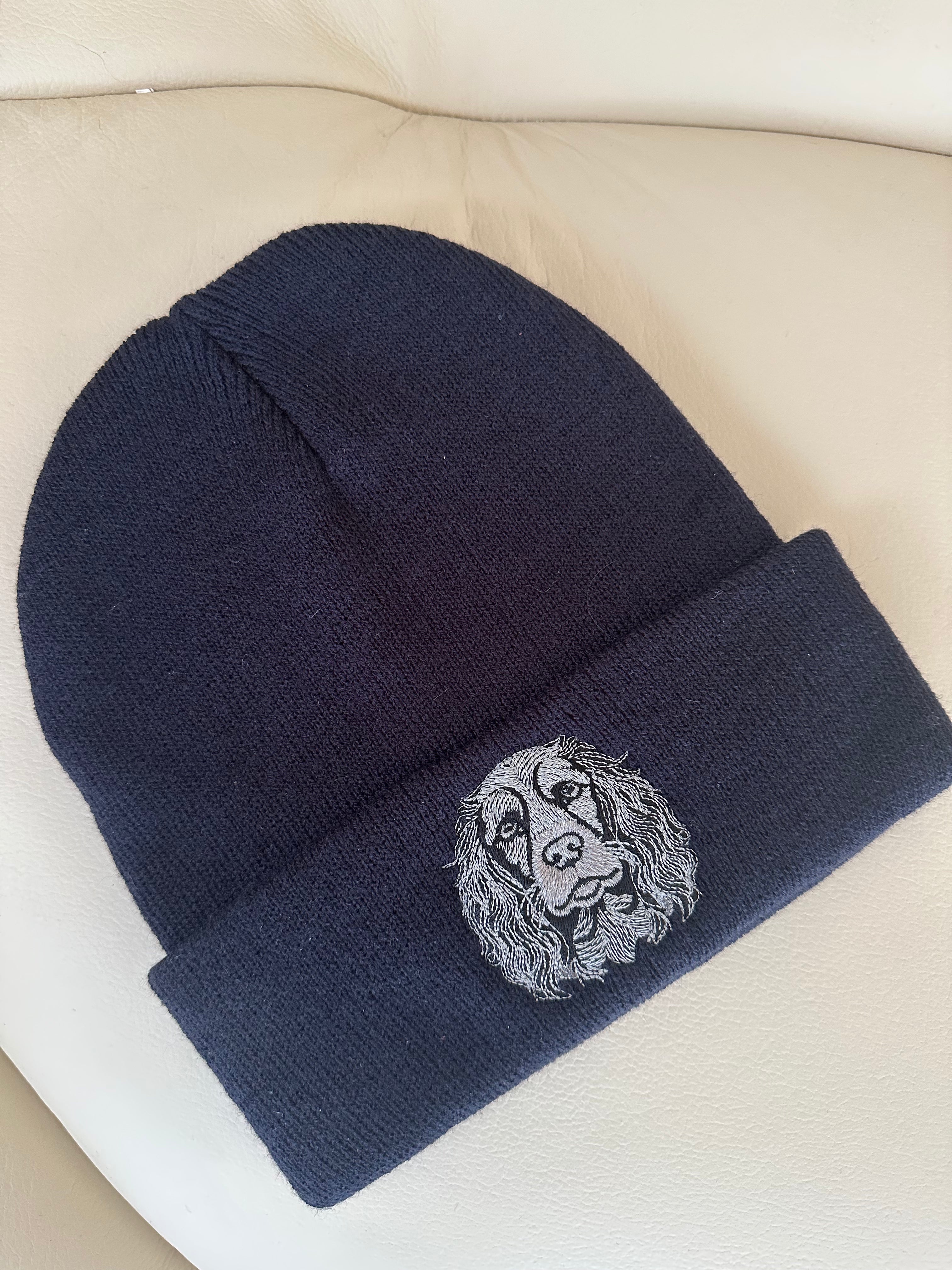 Navy blue beanie with a embroidered design on a beige surface