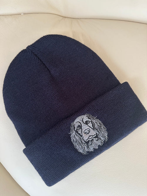 Navy blue beanie with a embroidered design on a beige surface