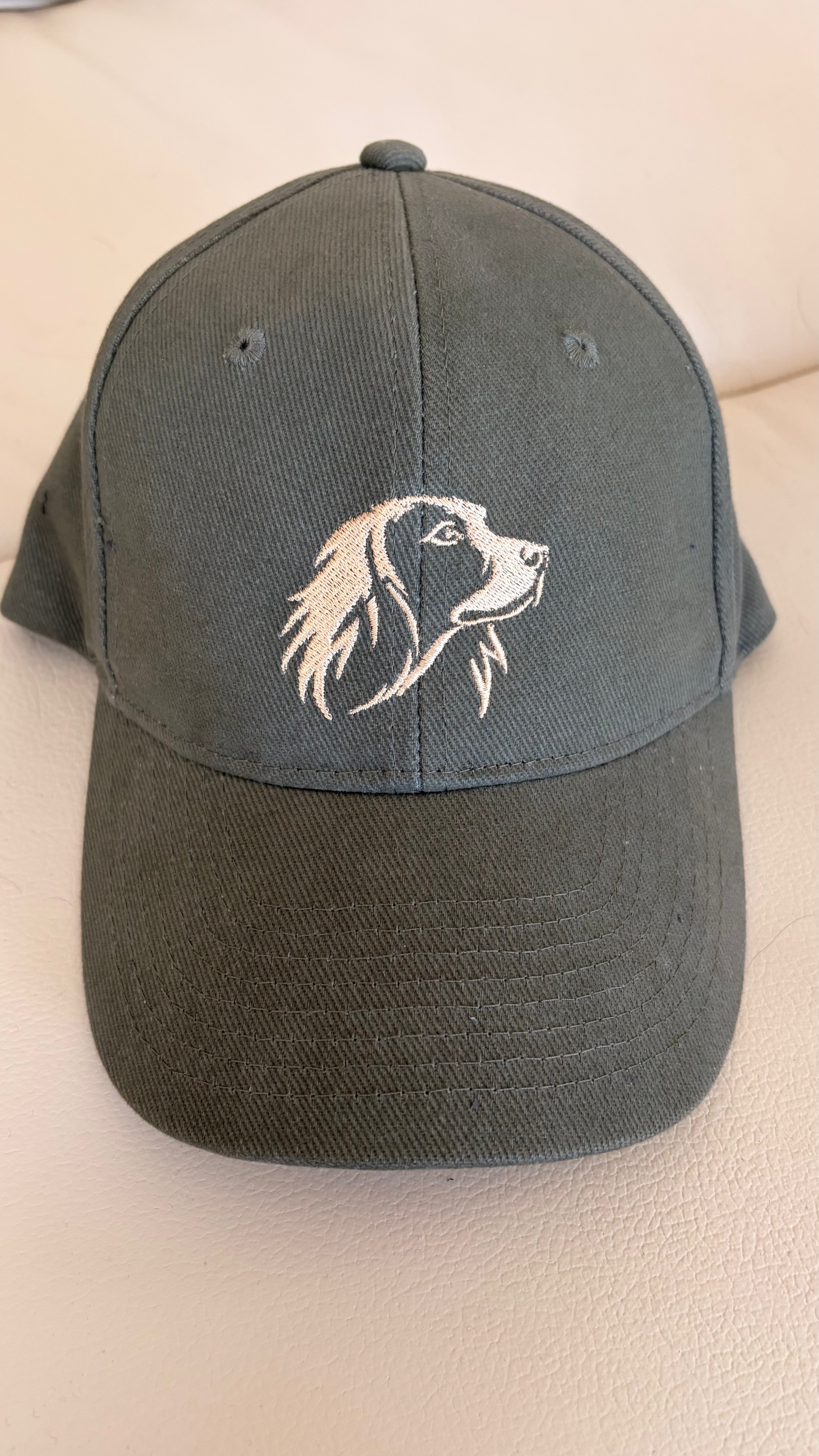 Olive green cap with a dog illustration on a beige surface