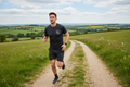 Man running on a dirt path in a scenic countryside setting