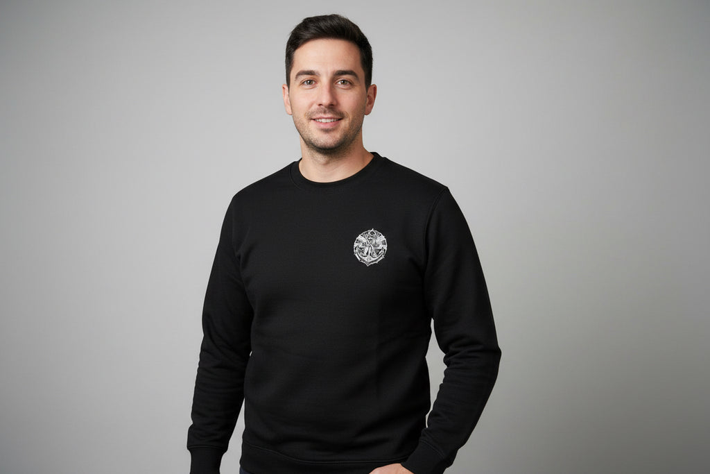 Man wearing a black sweatshirt with an anchor logo on a grey background
