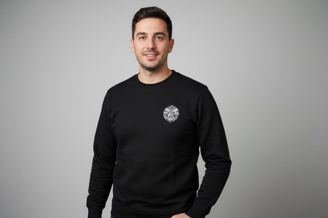 Man wearing a black sweatshirt with an anchor logo on a grey background