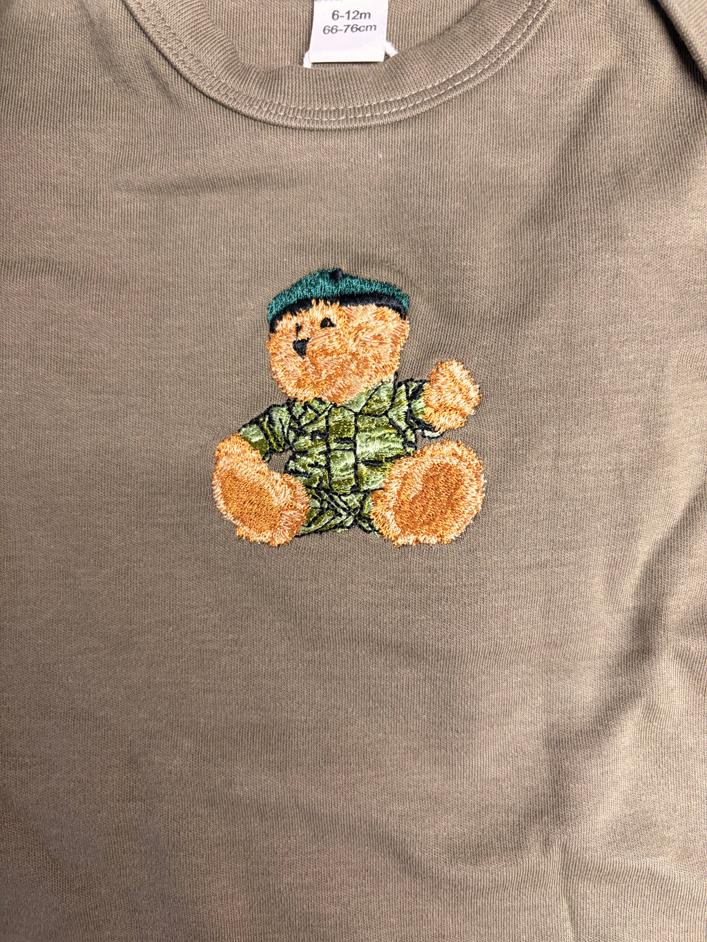 Olive baby vest with embroidered teddy bear design on a plain background