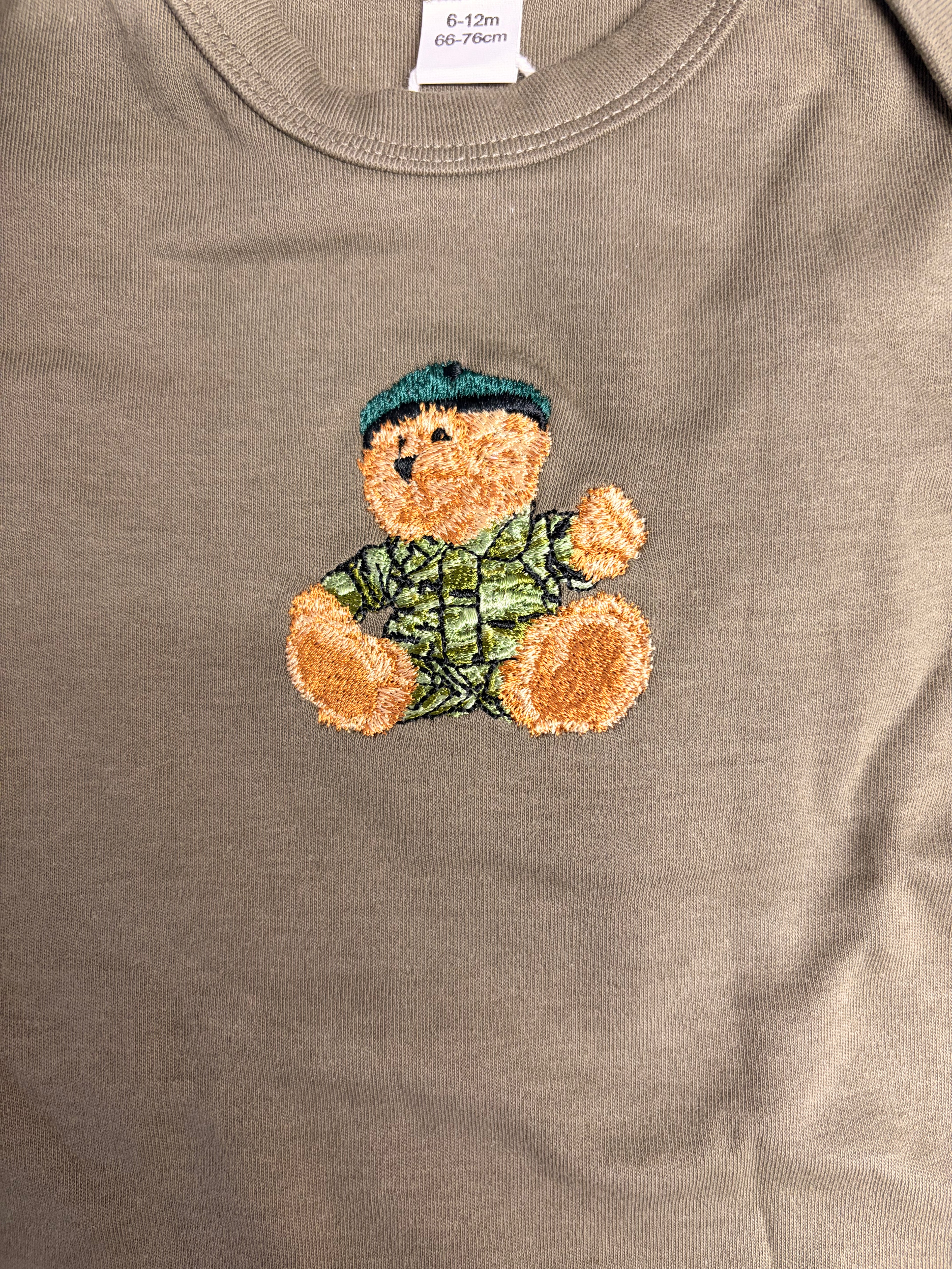Olive baby vest with embroidered teddy bear design on a plain background