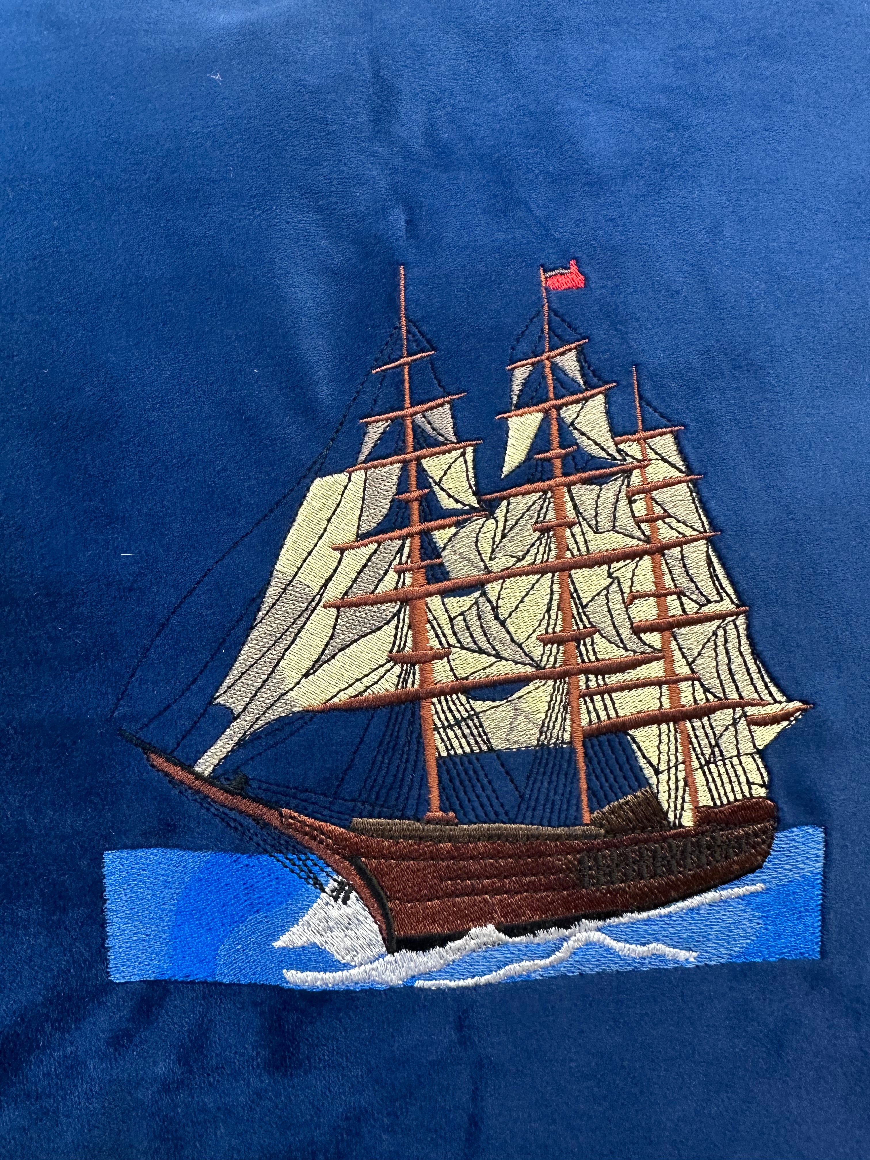 Embroidered ship design on a blue fabric background