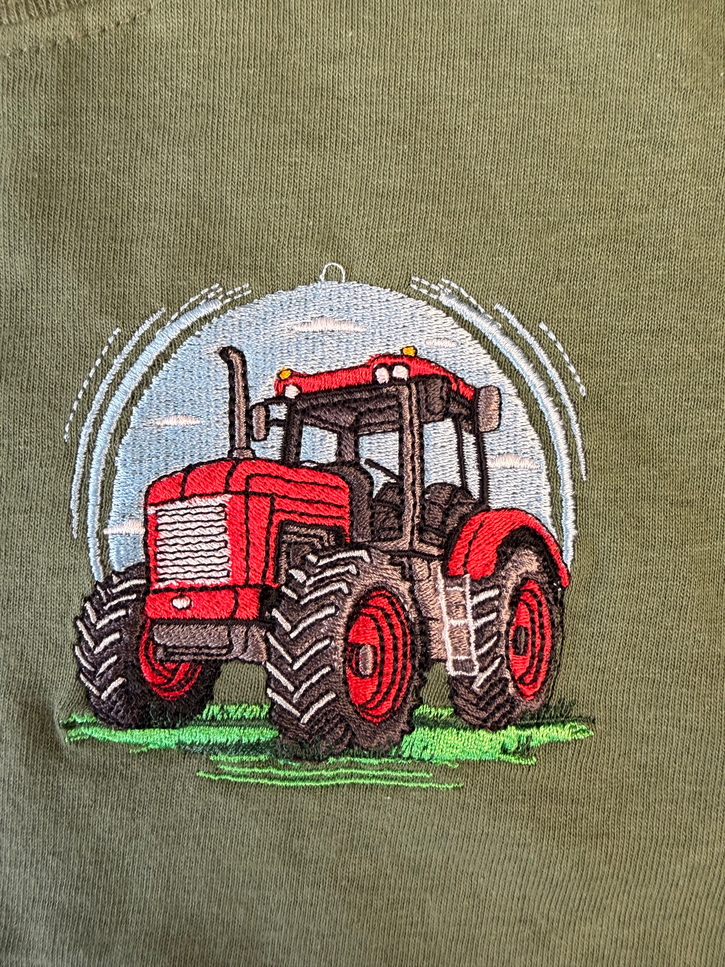 Red tractor embroidered on a green fabric background