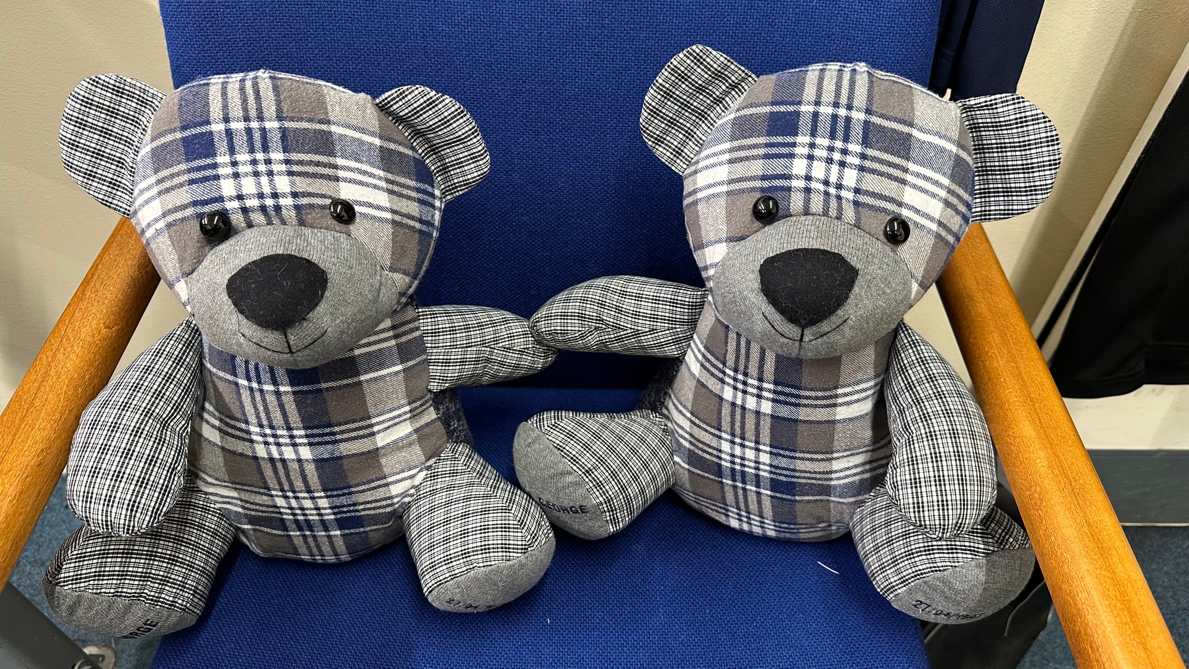 Two plaid teddy bears sitting on a blue chair.