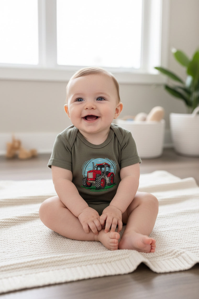 Baby sitting on a rug wearing a onesie with a red tractor graphic